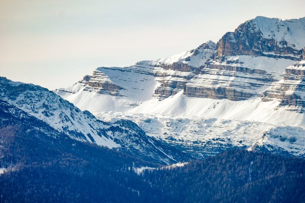 A beautiful shot of forested hills near the snowy mountain in Alberta and the Rockies, Canada
